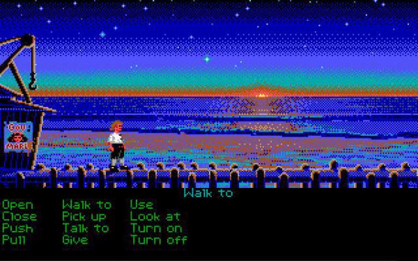 Pixelated screenshot from the 16-color EGA version of the classic point-and-click adventure game "The Secret of Monkey Island". The protagonist, Guybrush Threepwood, stands on a wooden dock overlooking an ocean horizon where a vibrant orange sunset meets a dark blue, starry night sky. To the left is a small wooden structure with a crane and a poster reading "Gov. MARLEY". The bottom third of the screen features the black SCUMM interface with bright green text commands such as "Walk to", "Open", "Pick up", and "Talk to."
