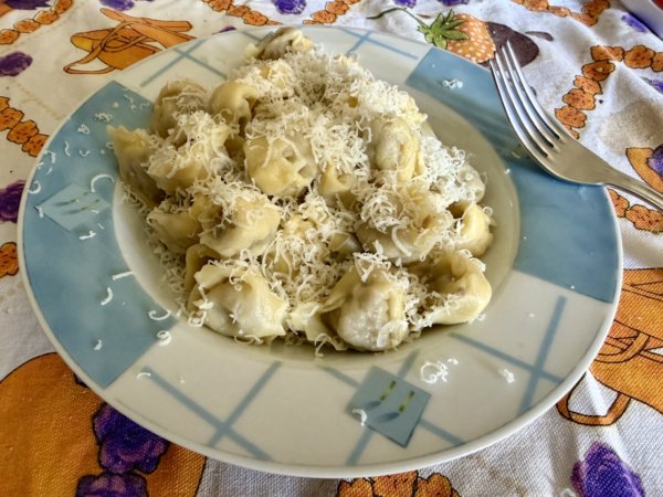 A dish full of tortellini, with some parmigiano on it